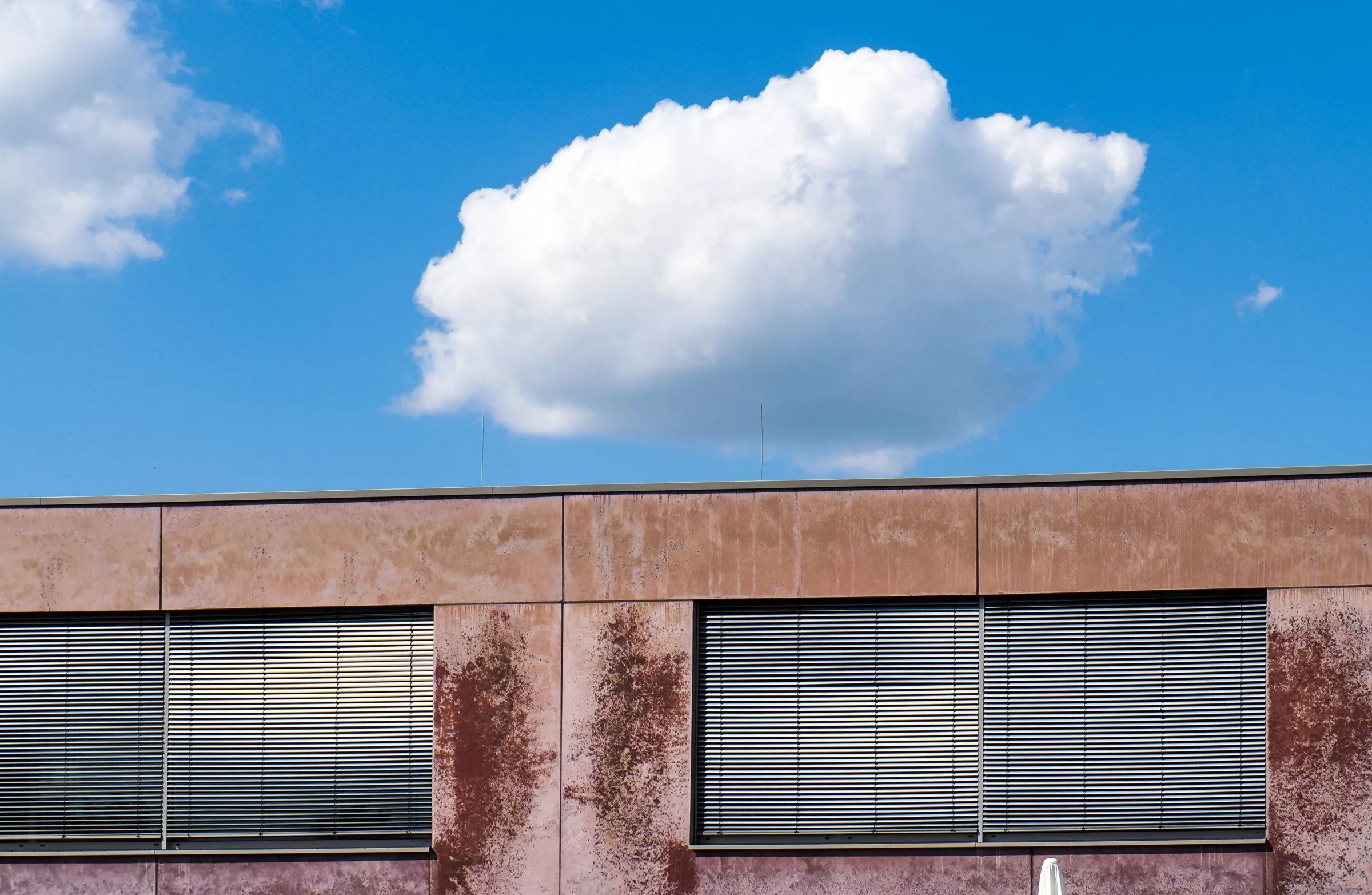 Geschlossene Fenster des Kulturzentrums vor blauem Himmel in Trudering