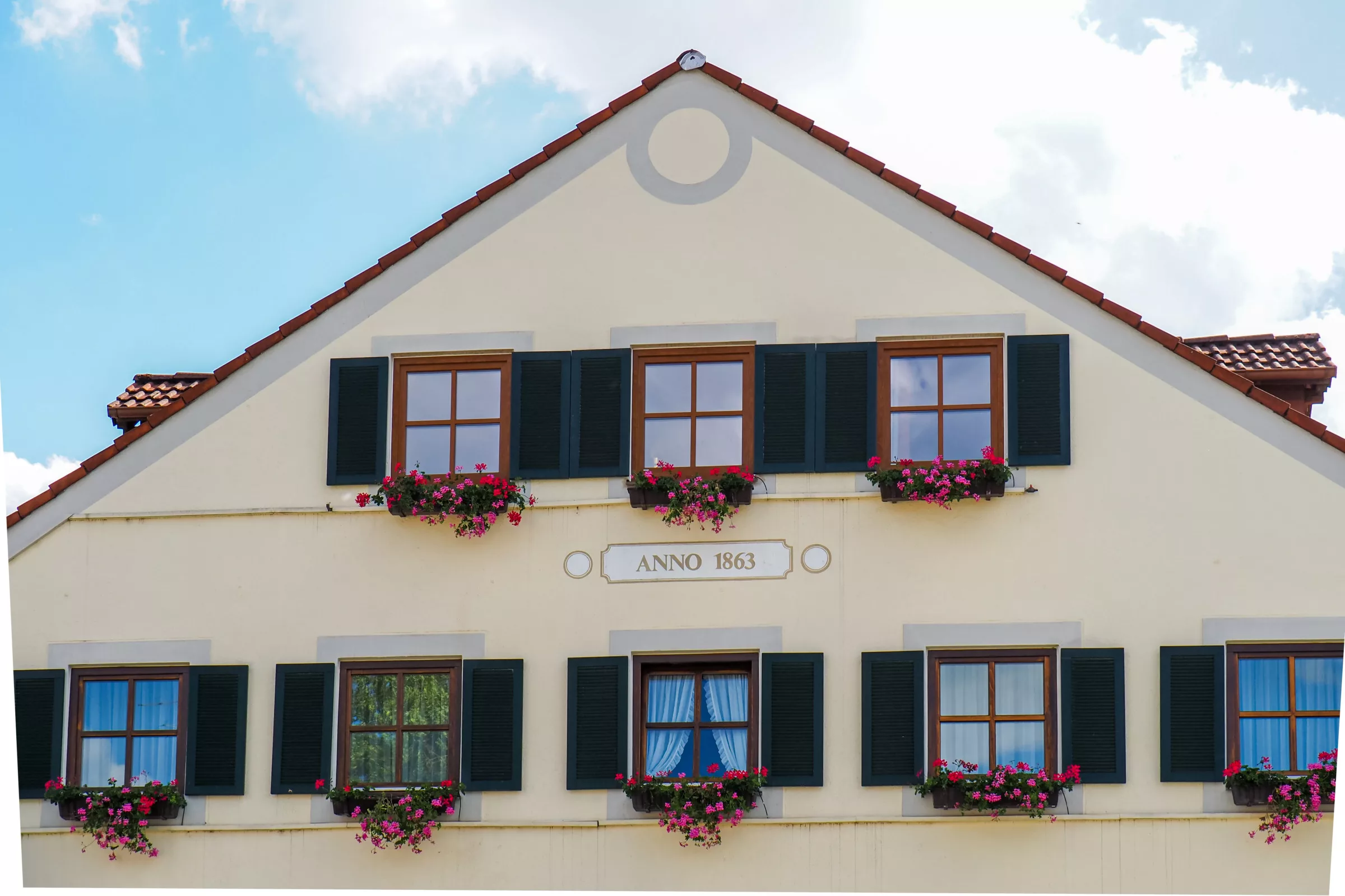 Renoviertes Gebäude anno 1863 mit Geranien, Fensterläden und weißen Vorhängen in Trudering