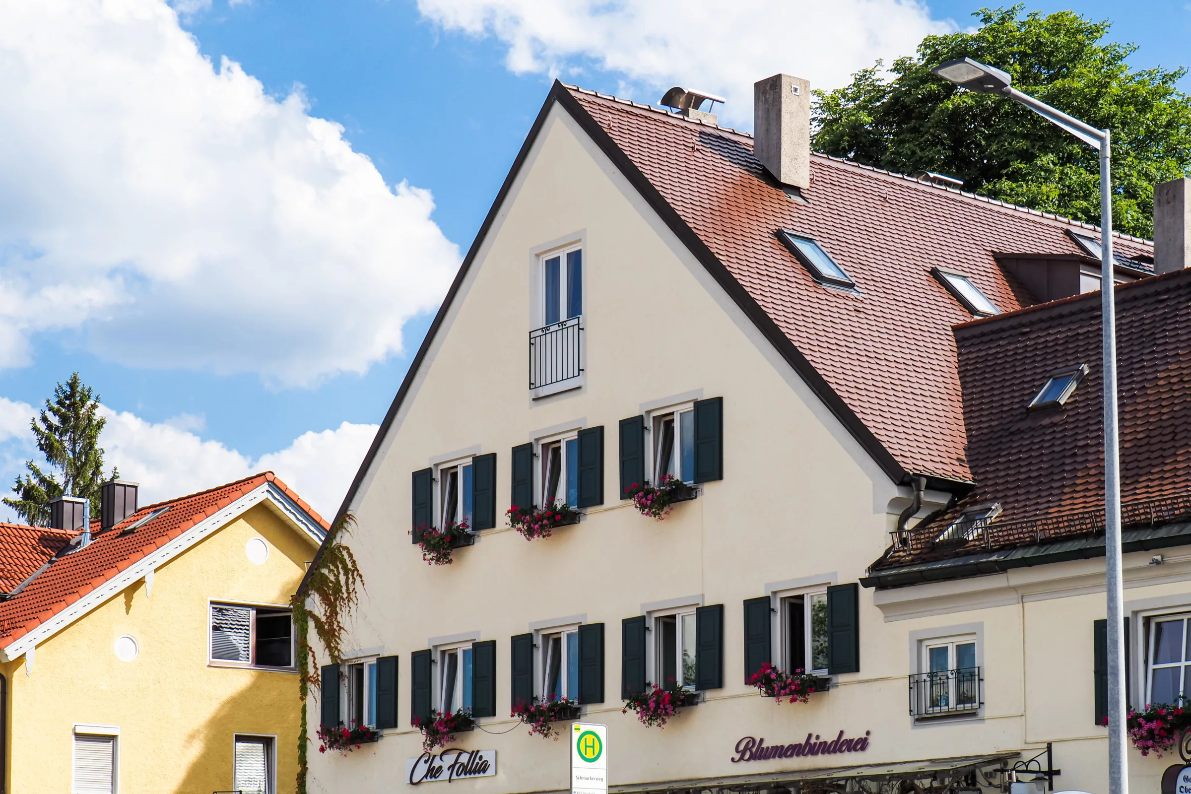 Renoviertes Haus mit Geschäften, Geranien und Fensterläden