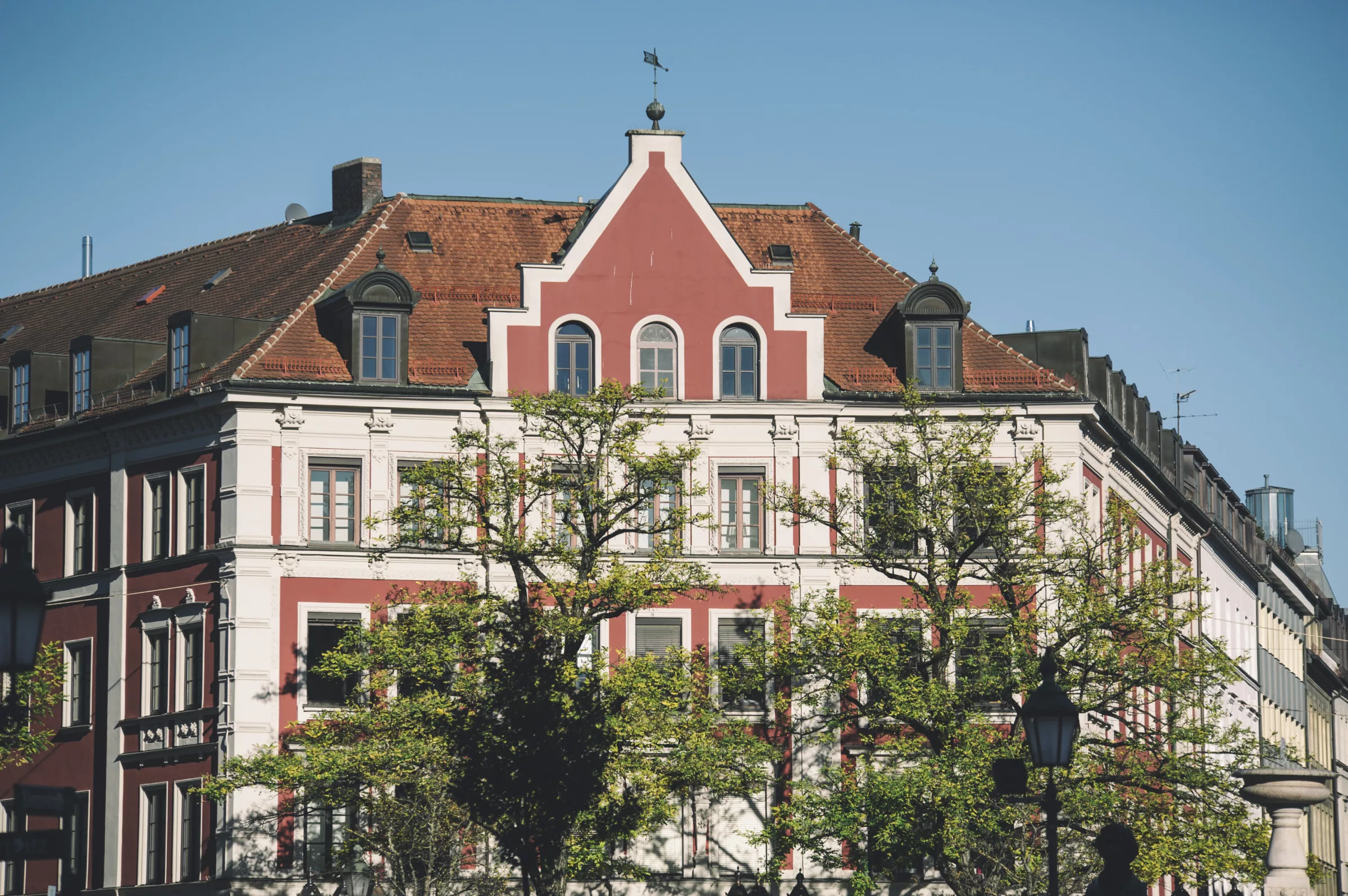 Historisches Gebäude mit rotem Dach und Bäumen in der Ludwigvorstadt-Isarvorstadt
