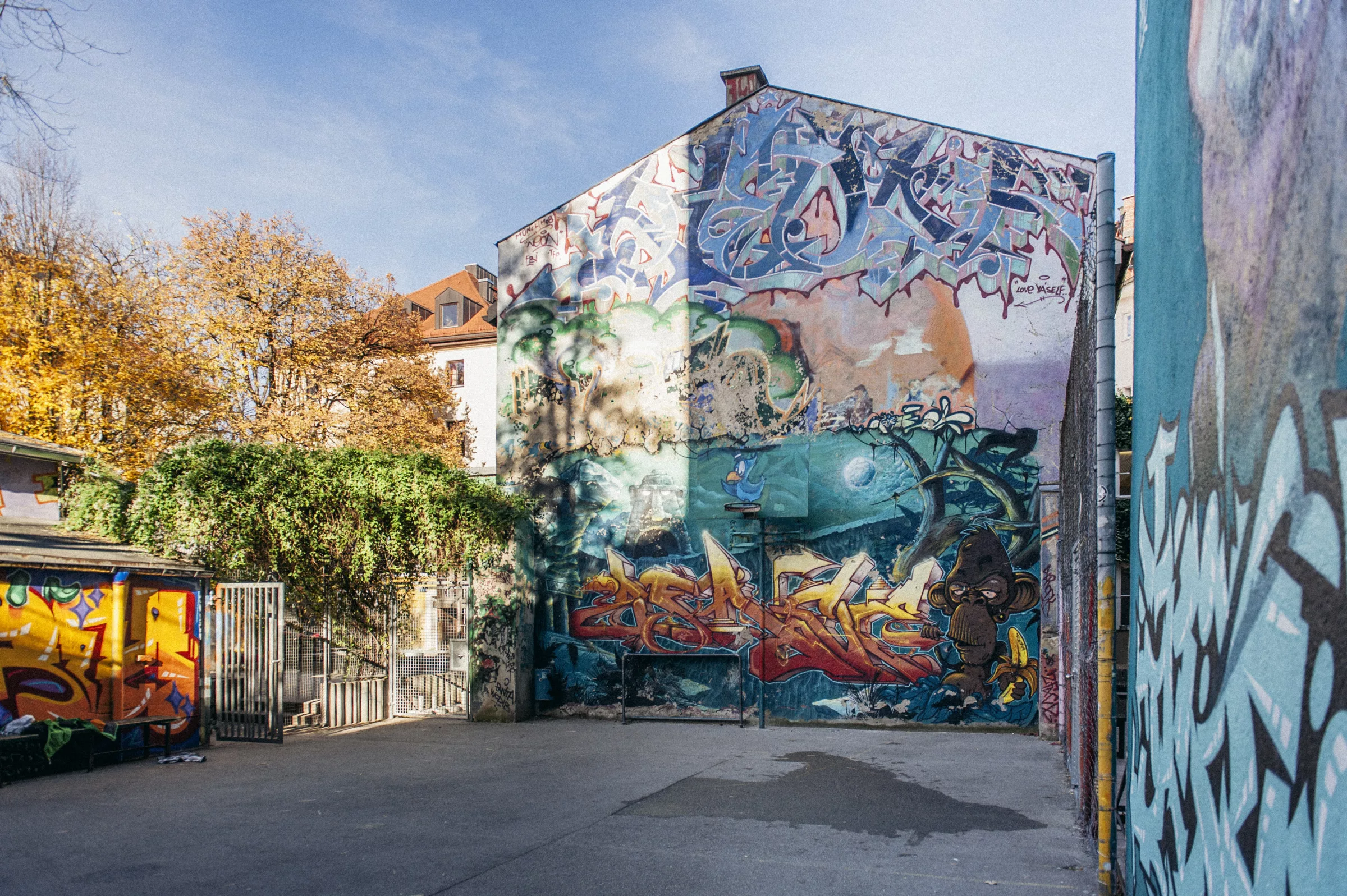 Hausrückwand, die mit bunten Graffiti besprüht ist.
