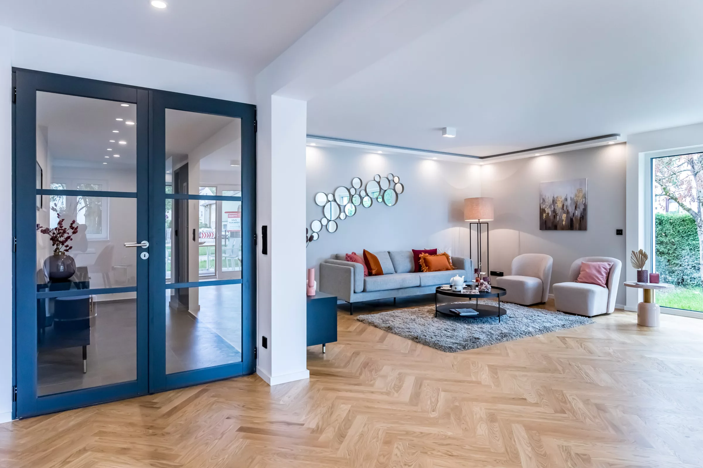 Modern eingerichtetes Wohnzimmer mit Holzboden und hohen Fenstern