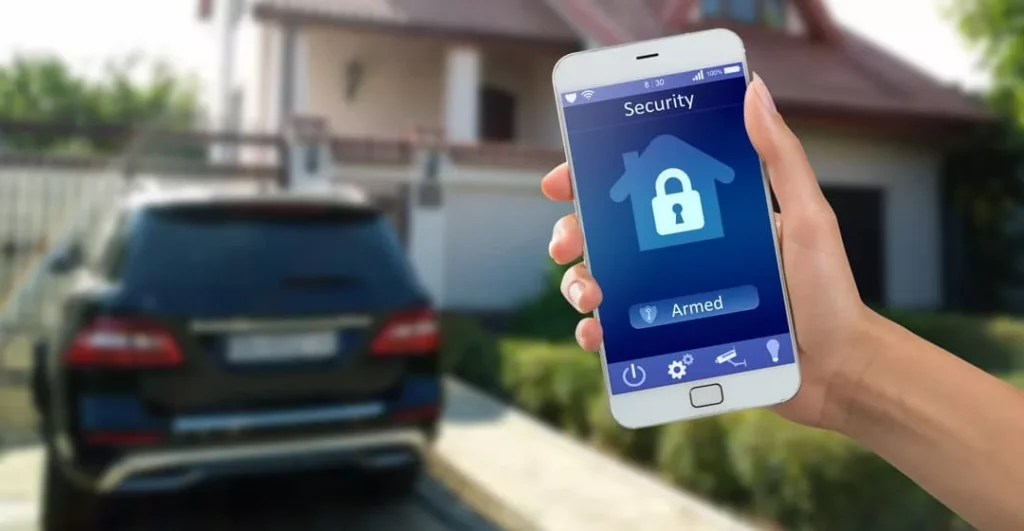 Person hält Smart Home app auf dem Handy vor seinem Haus in die Luft