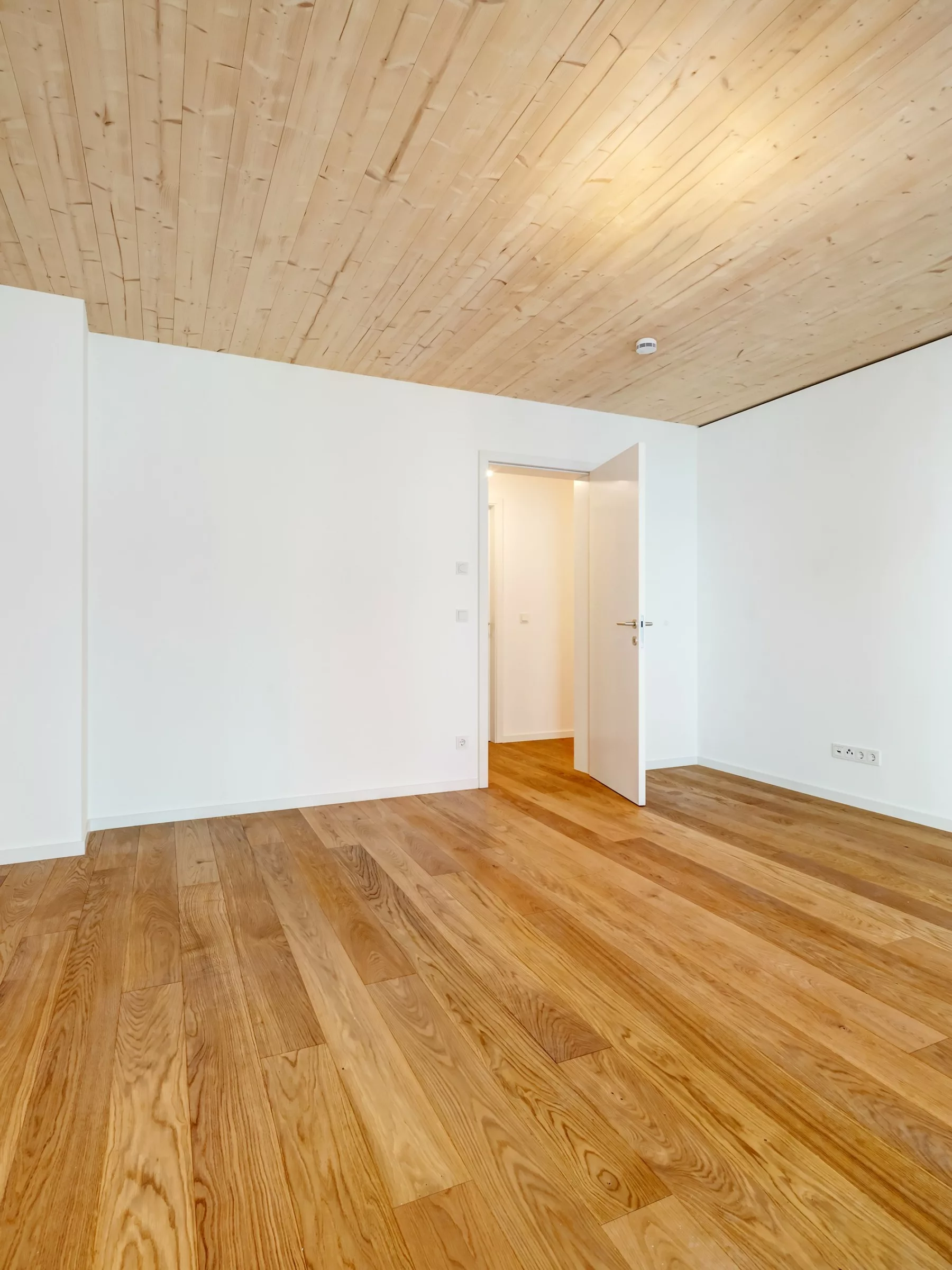 Heller Raum mit Holzfußboden und offener Tür
