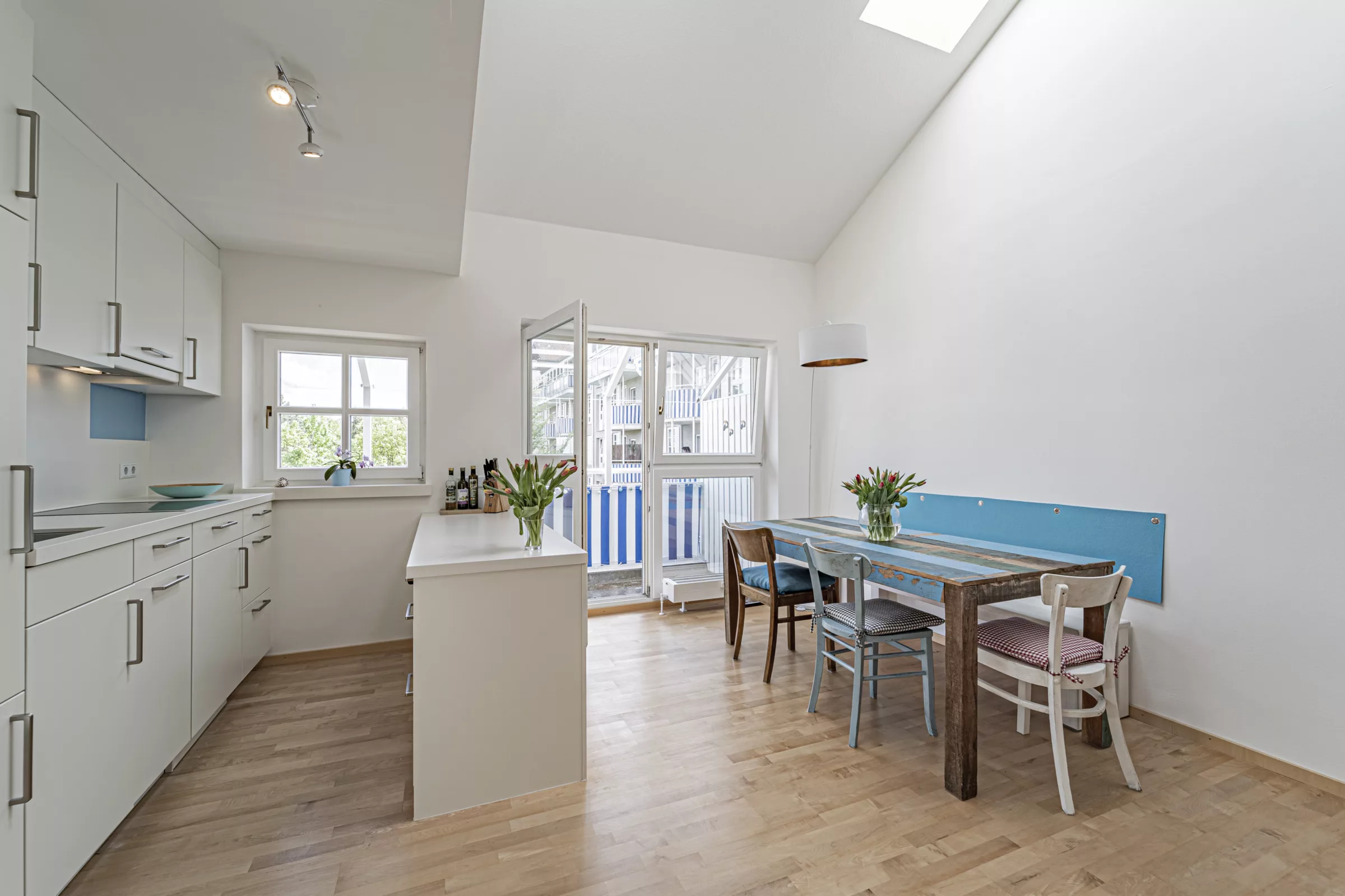 Helle moderne Küche mit Esstisch und Blumen.