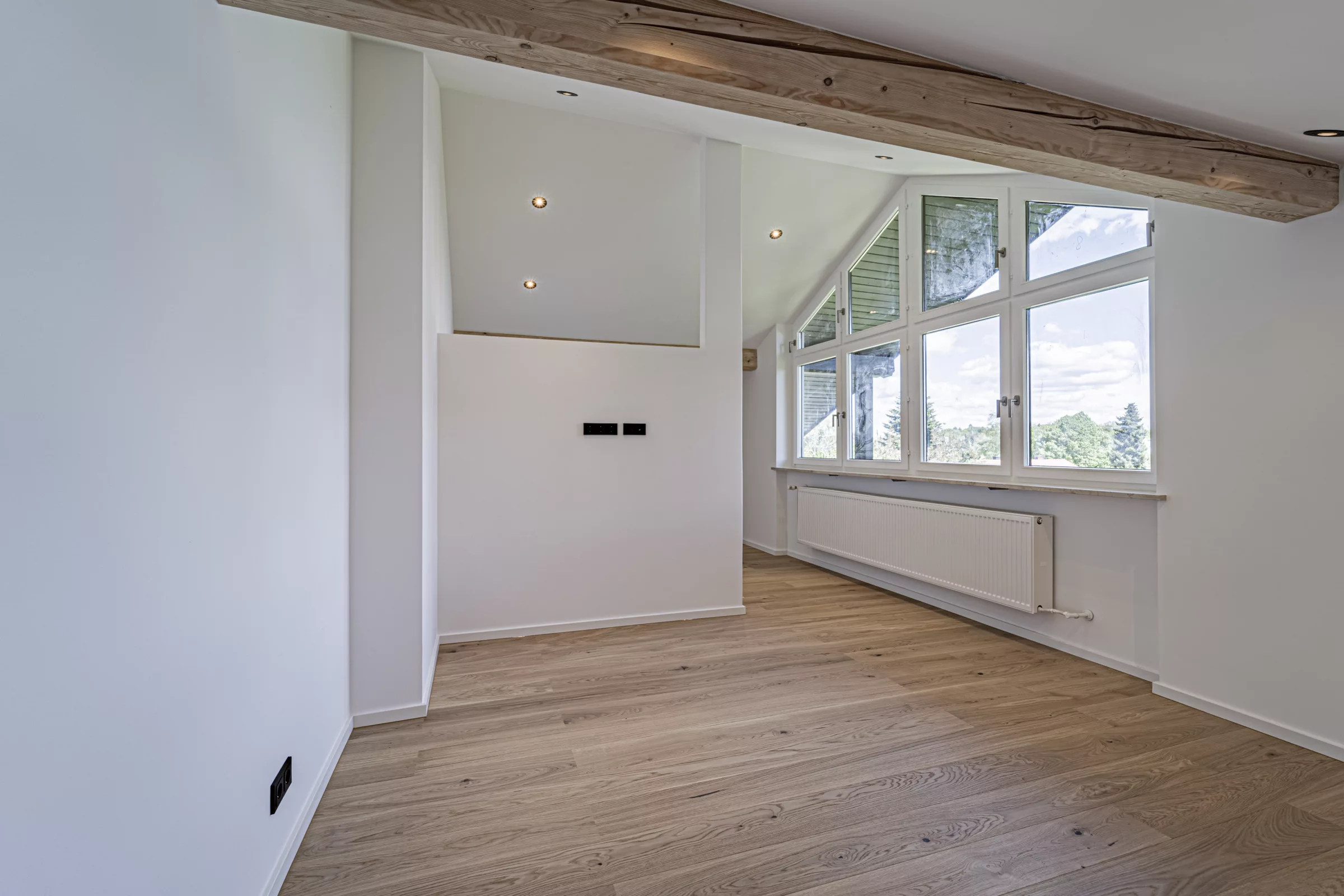 Helles Zimmer mit Holzboden und großen Fenstern