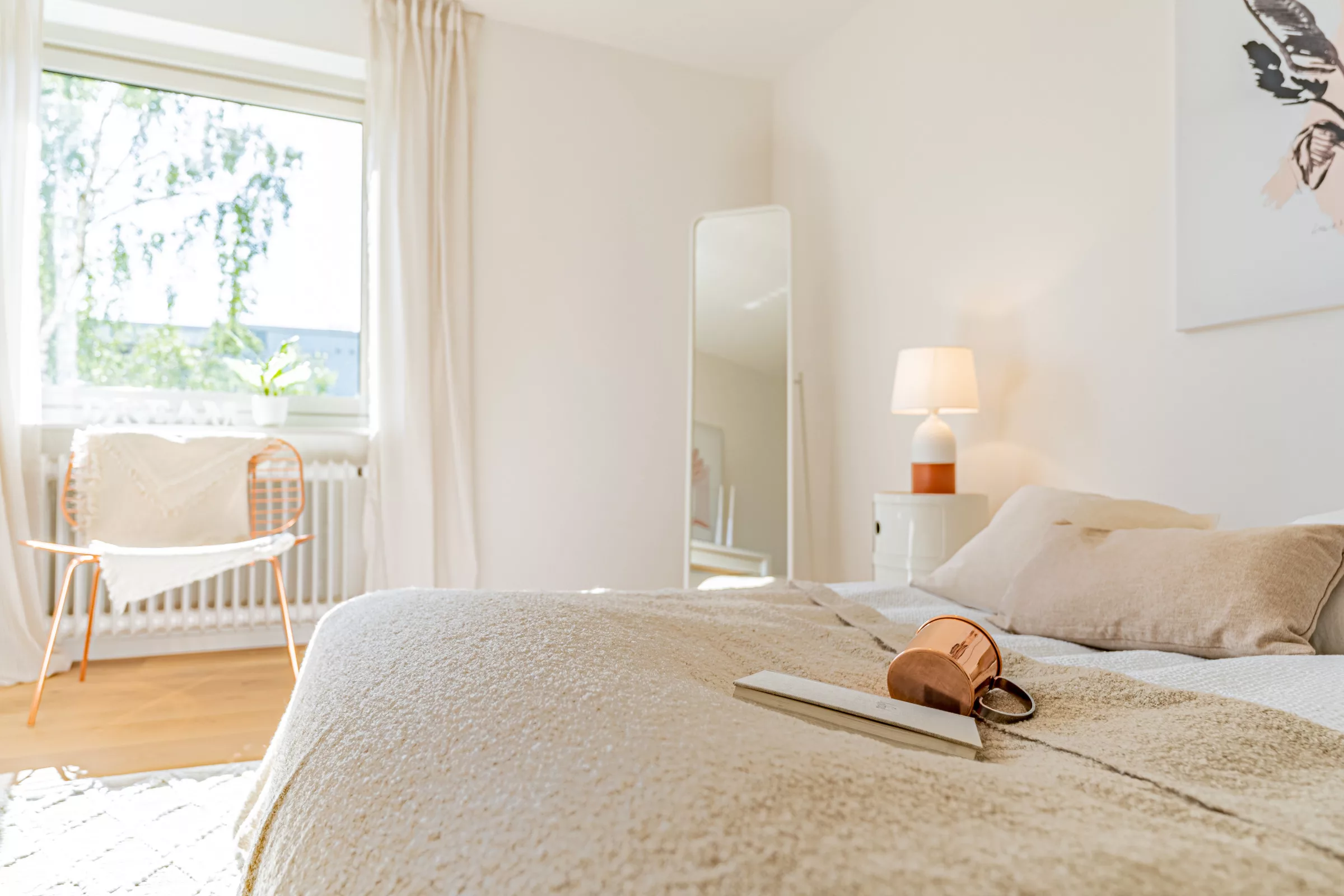 Helles Schlafzimmer mit bed, Beistelltisch und Spiegel.