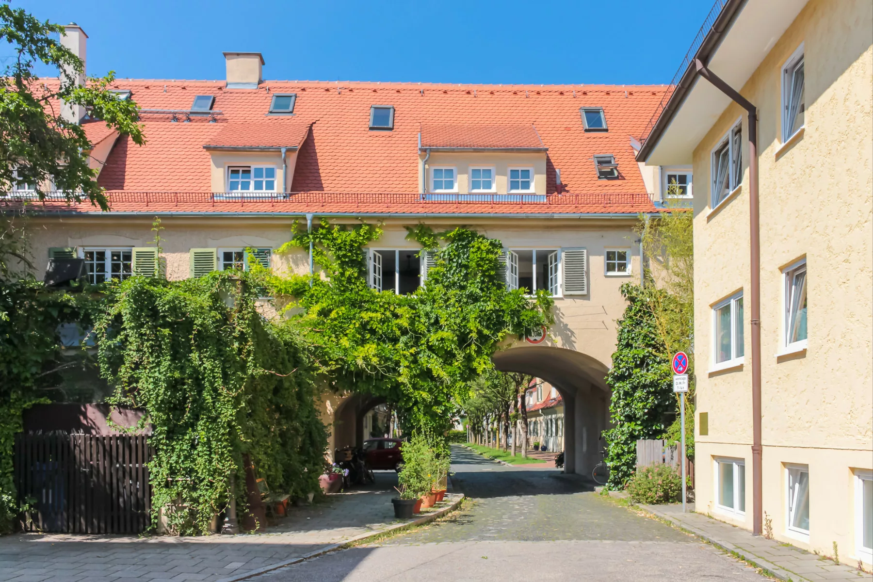 Wohngebäude mit begrünten Fassaden und architektonischem Durchgang in Laim