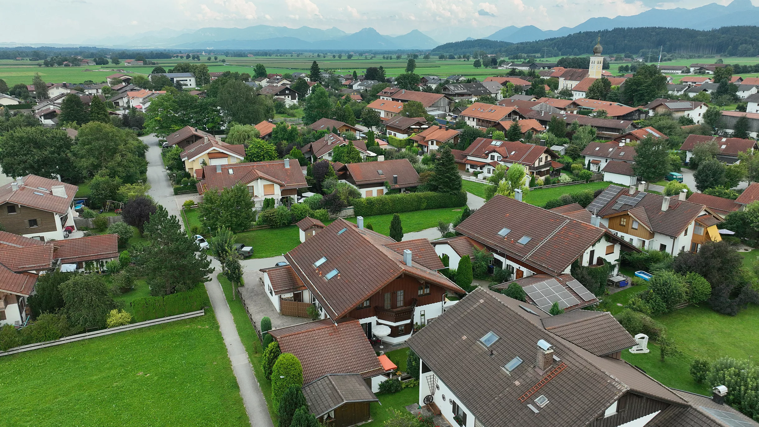 Luftaufnahme von Bruckmühl mit Bergen im Hintergrund.
