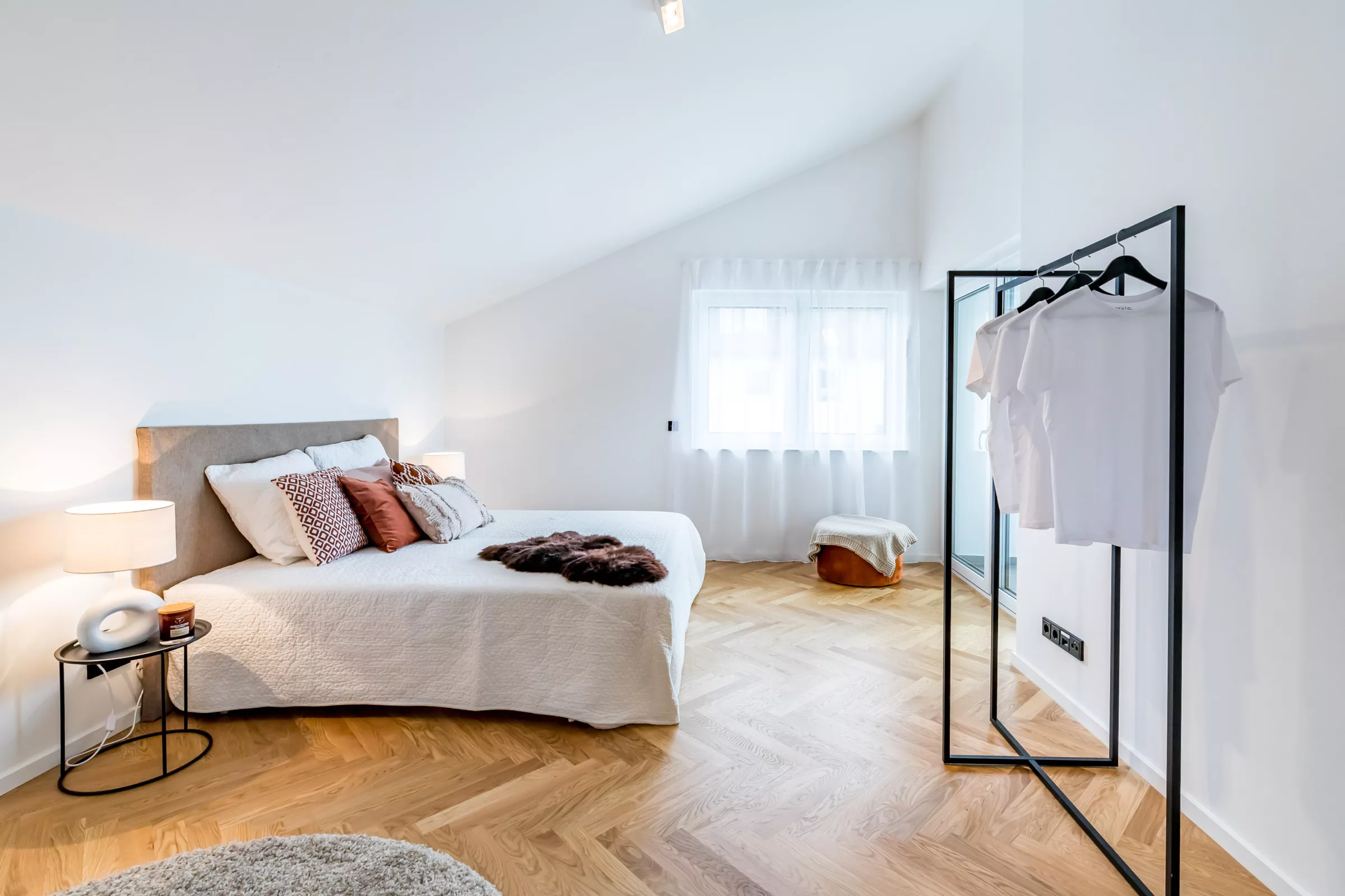 Helles Schlafzimmer mit moderner Einrichtung und Spiegel.