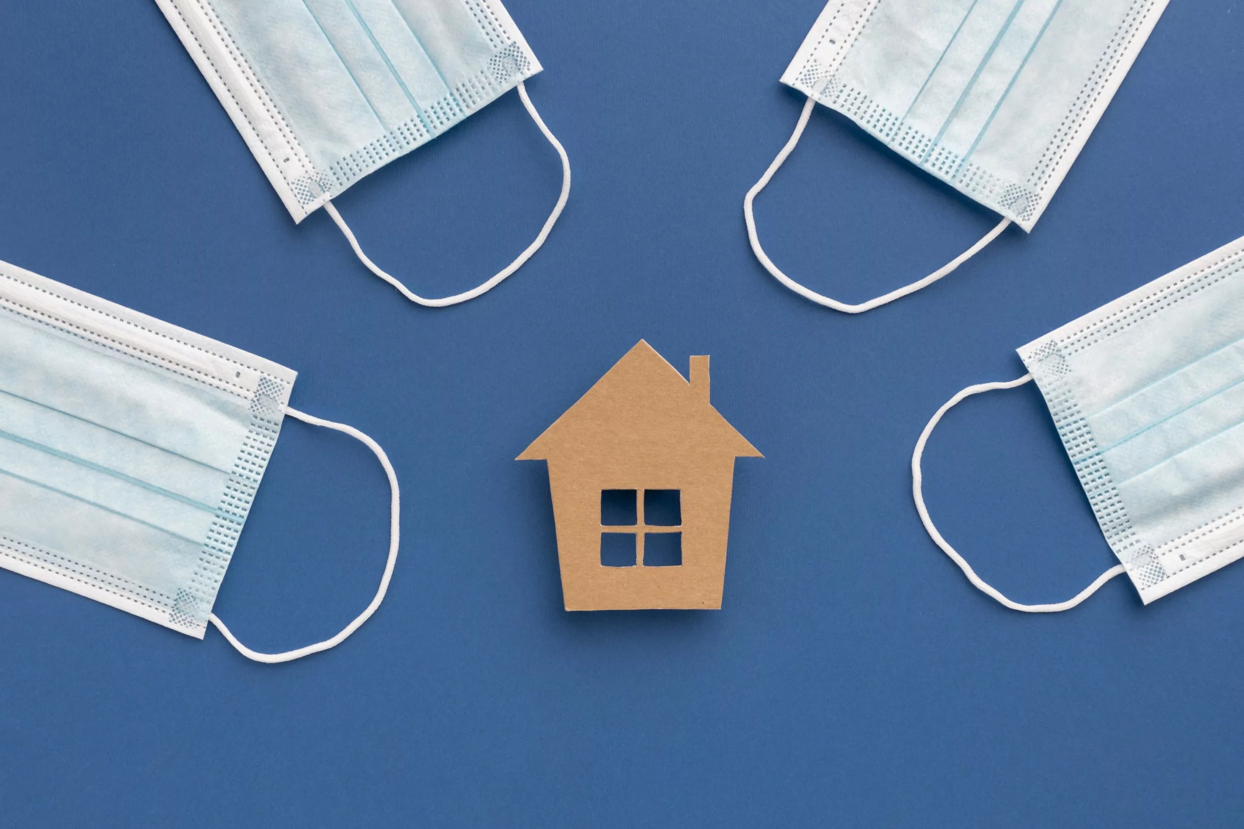 Schutzmasken um ein Haus aus Papier