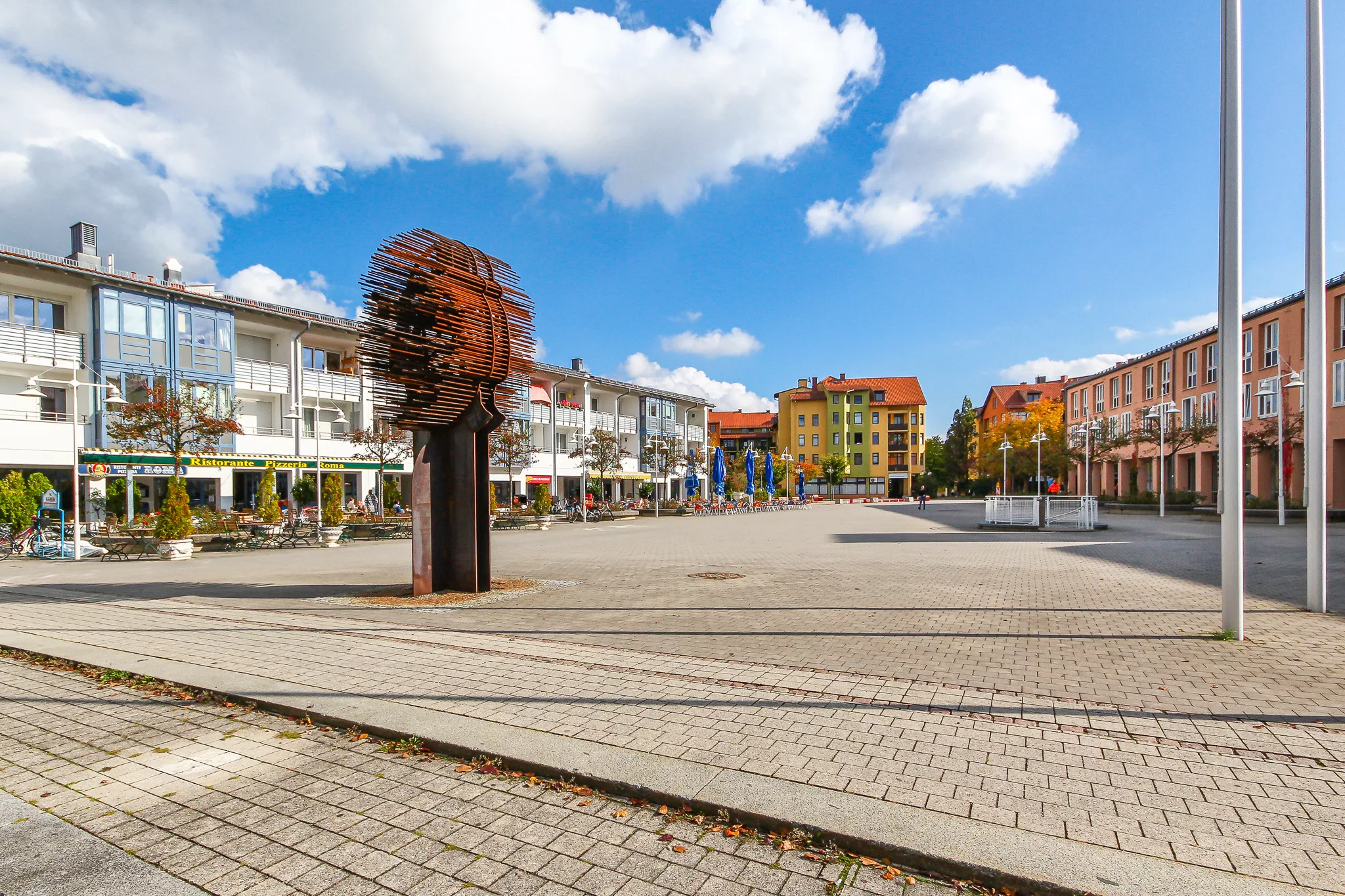 Platz mit Skulptur und bunten Gebäuden in Garching