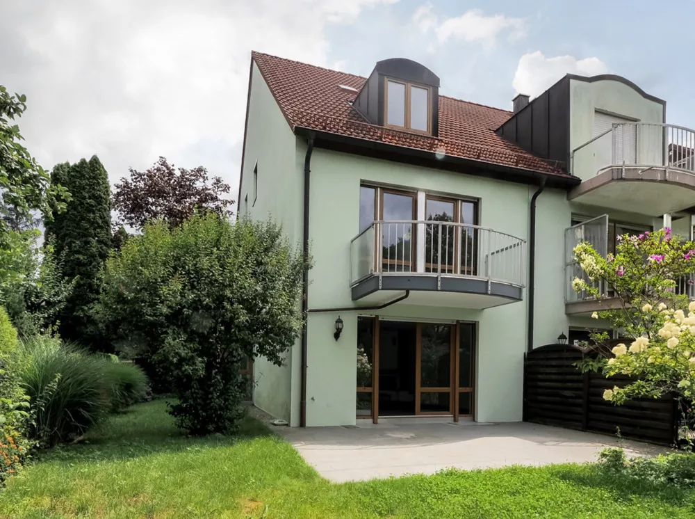 Helles Haus mit Balkon und Gartenbereich.