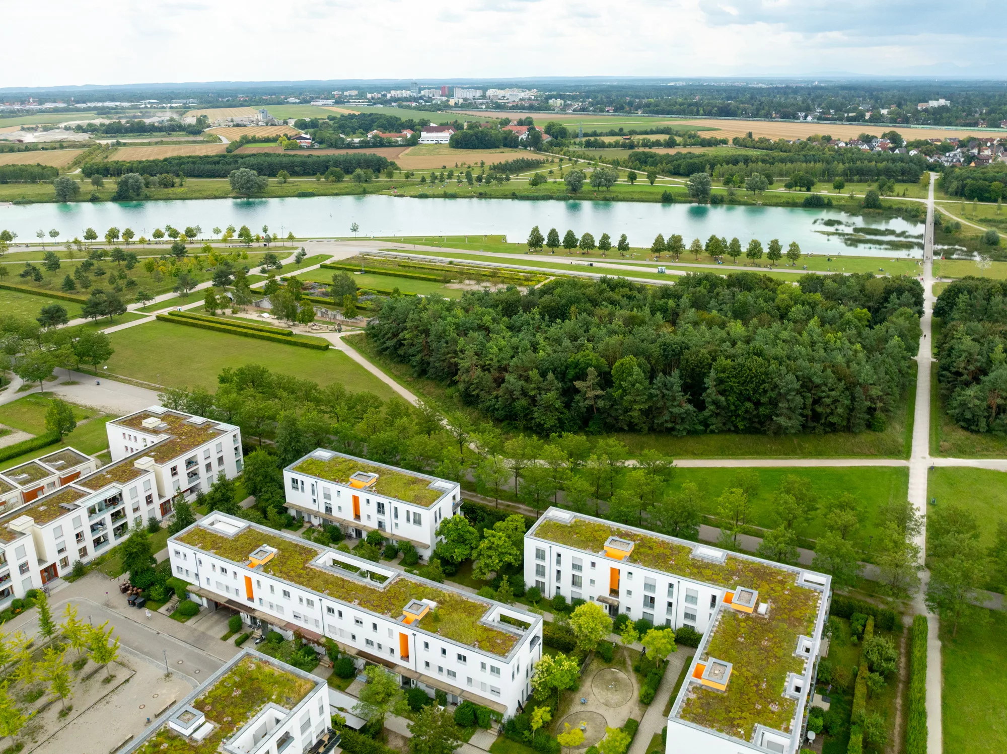 Luftaufnahme von Wohnungen und Grünflächen am Wasser.
