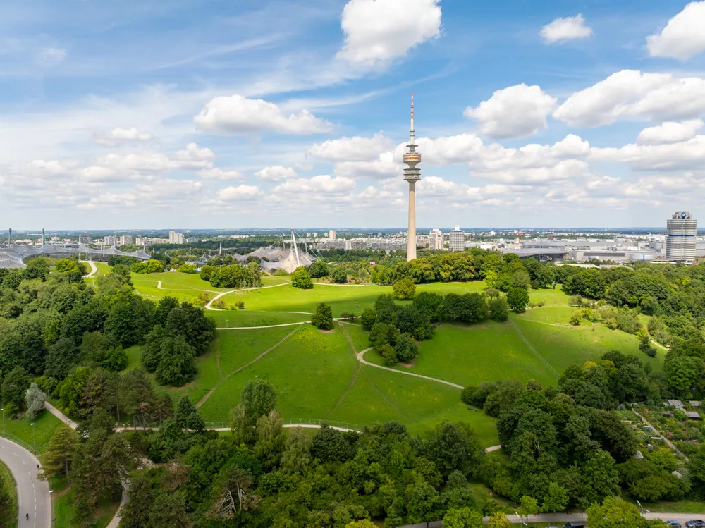 Panorama über grüne Landschaft und Stadtansicht vom Olympiaberg mit dem Olympiaturm.