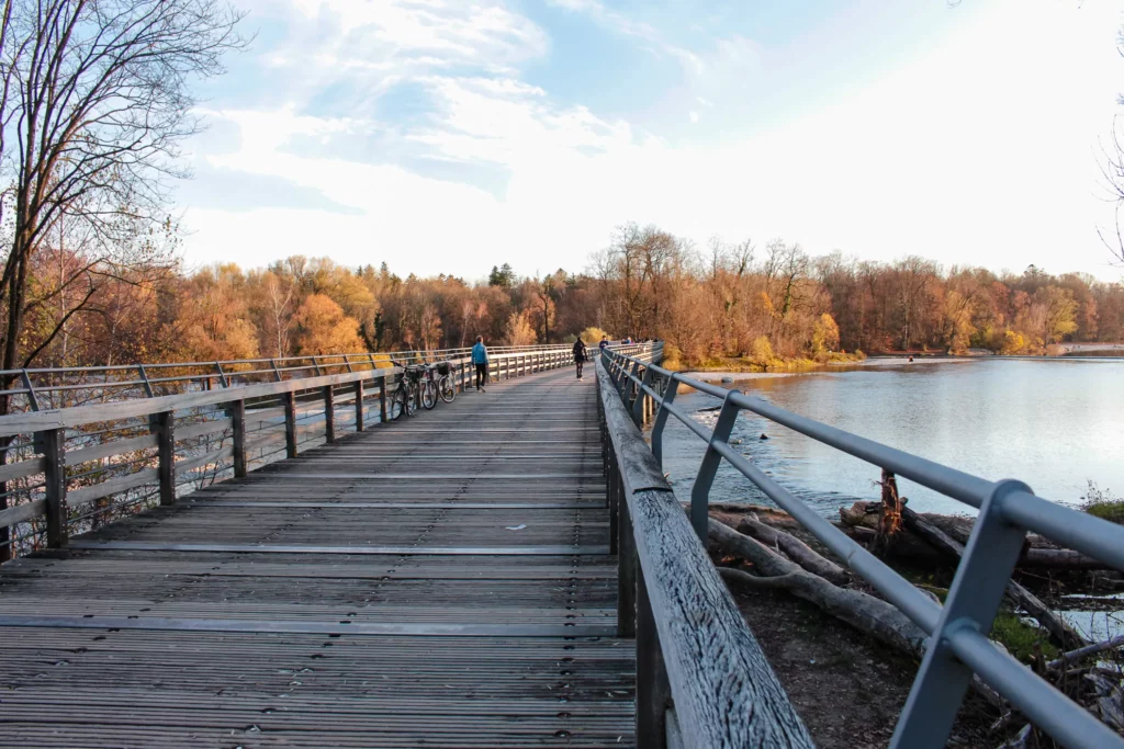 Holzbrücke am Wasser mit herbstlichen Bäumen in Sendling