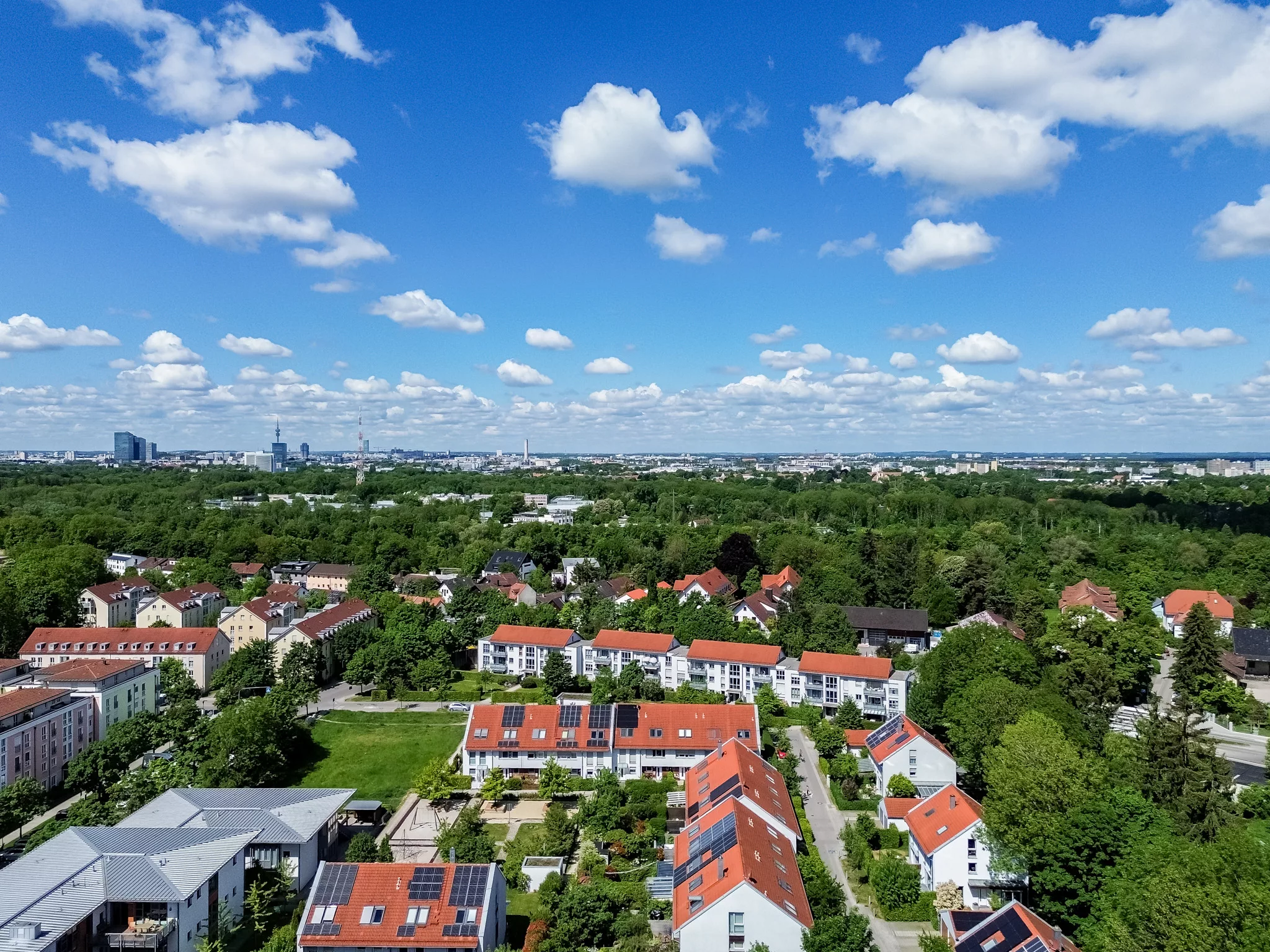 Blick auf eine grüne Stadtlandschaft mit Wolken.