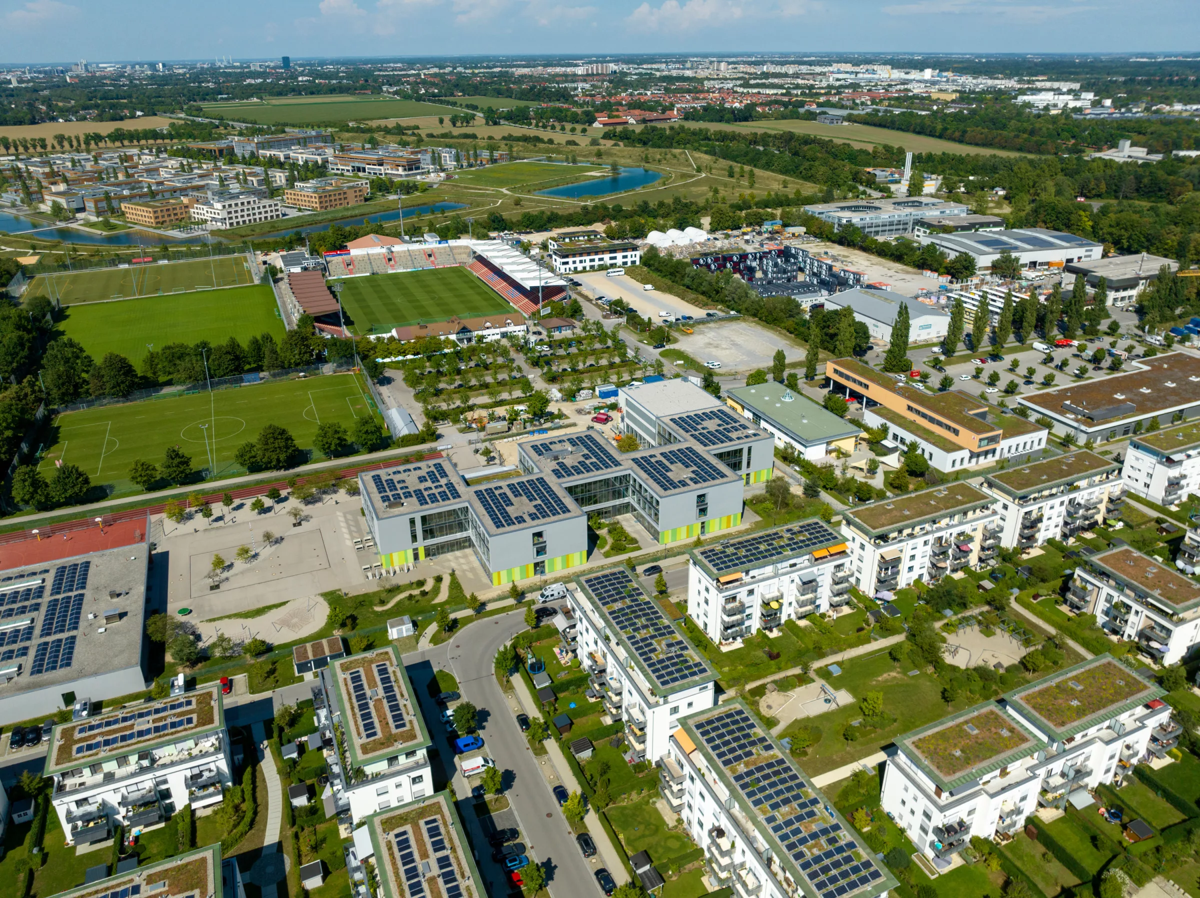 Luftaufnahme eines modernen Stadtviertels von Unterhaching-Taufkirchen mit Sportanlagen.