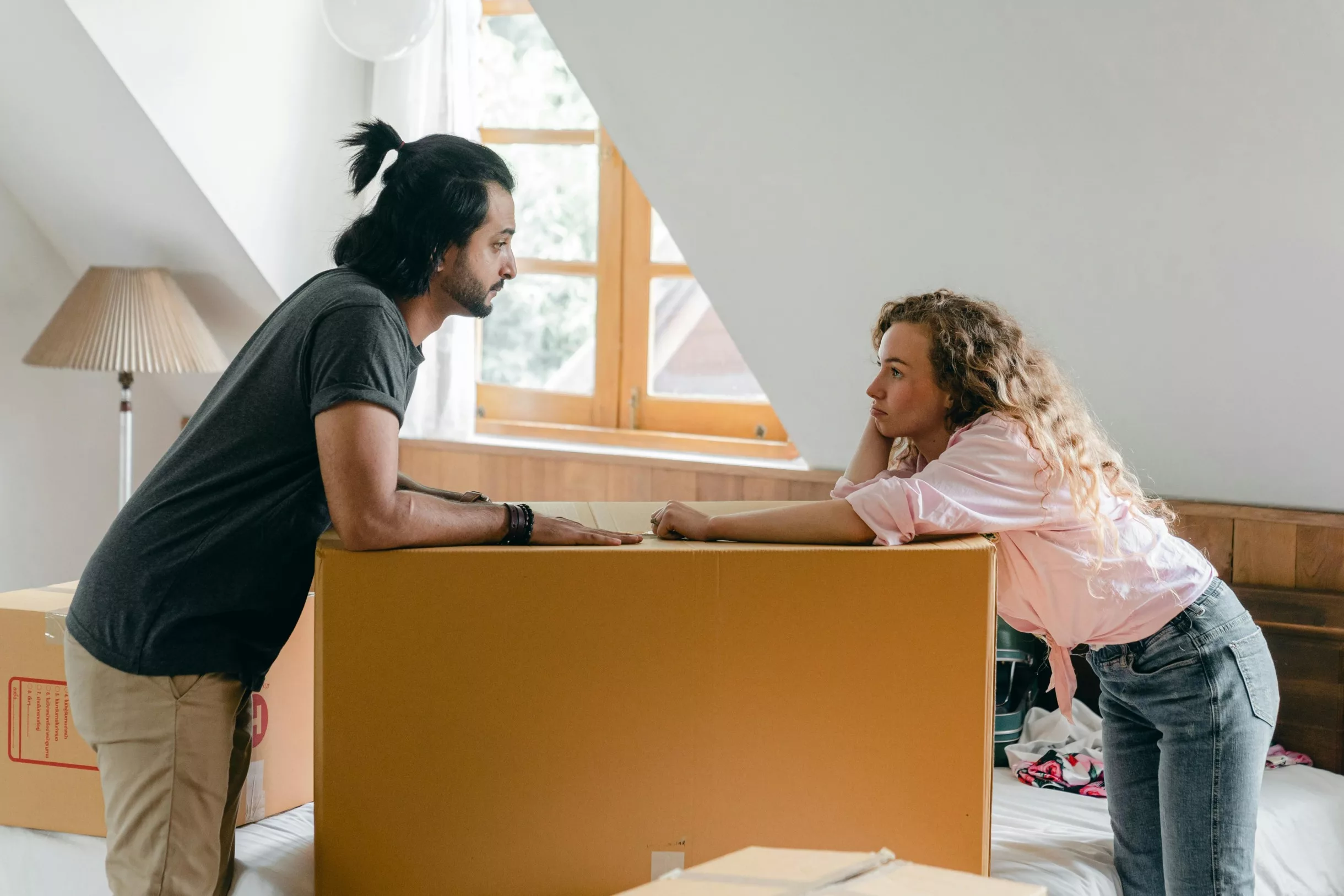Paar mit Umzugskartons diskutiert in einem Zimmer.