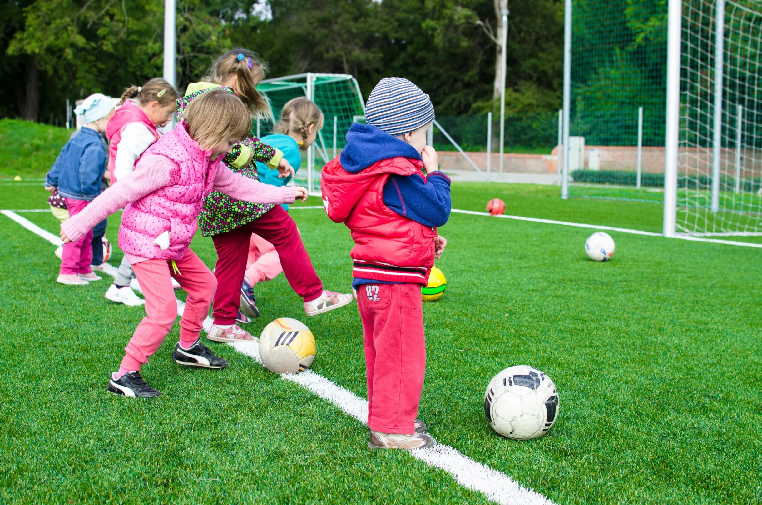 Kinder spielen Fußball auf dem Sportplatz.