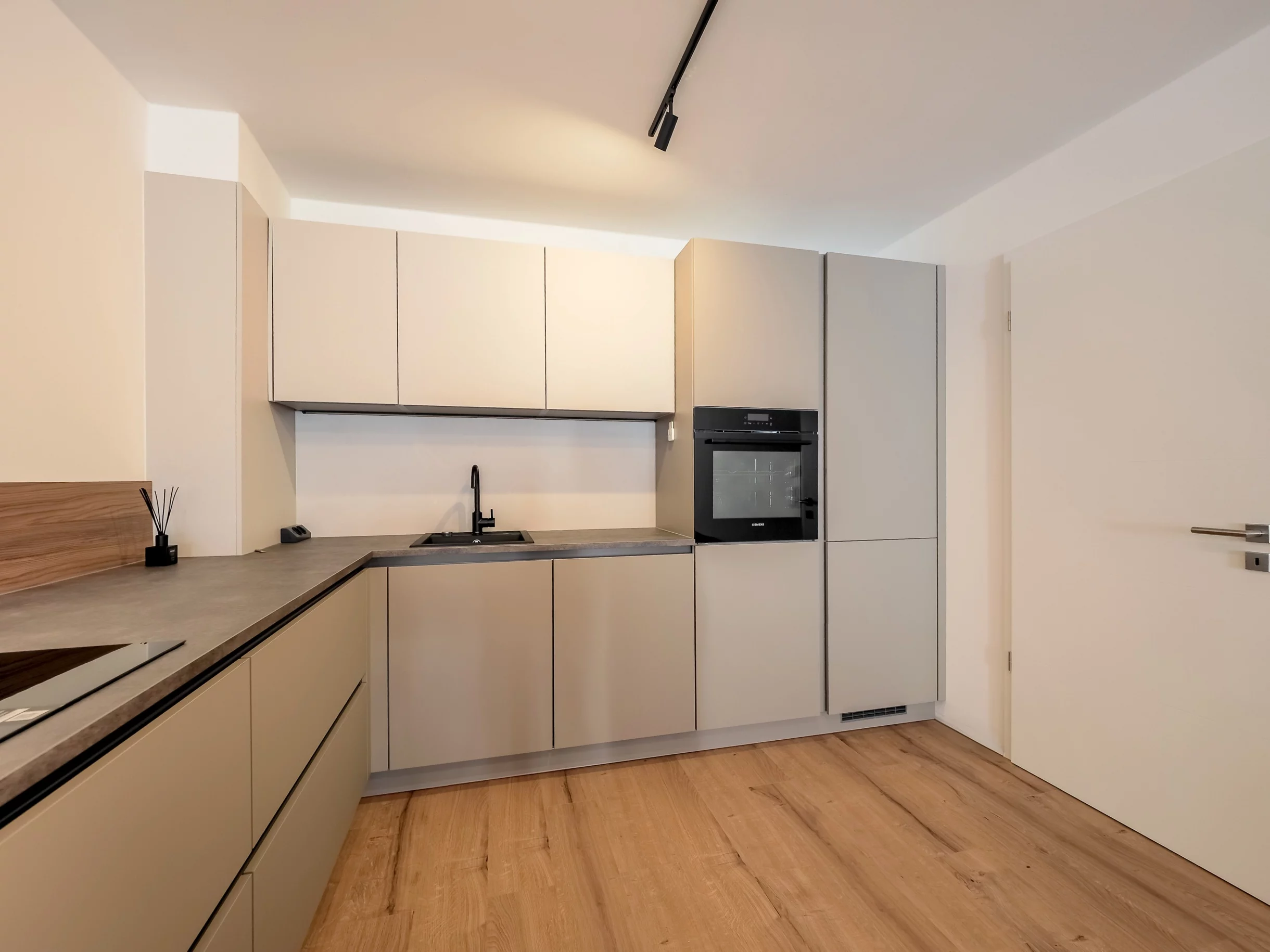 Moderne Küche mit hellen Schränken und Holzfußboden.