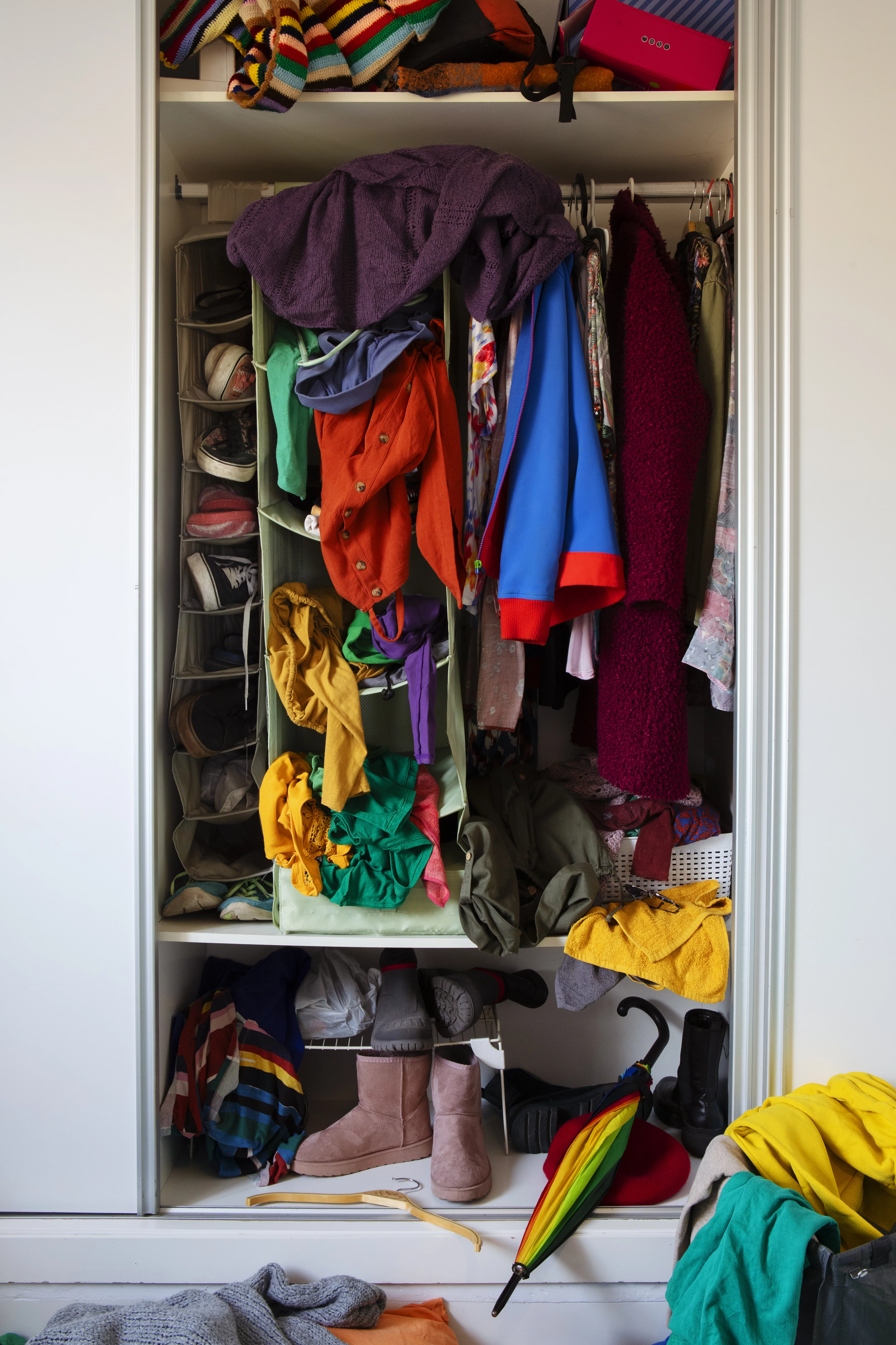 Überfüllter Kleiderschrank mit bunten Kleidungsstücken.