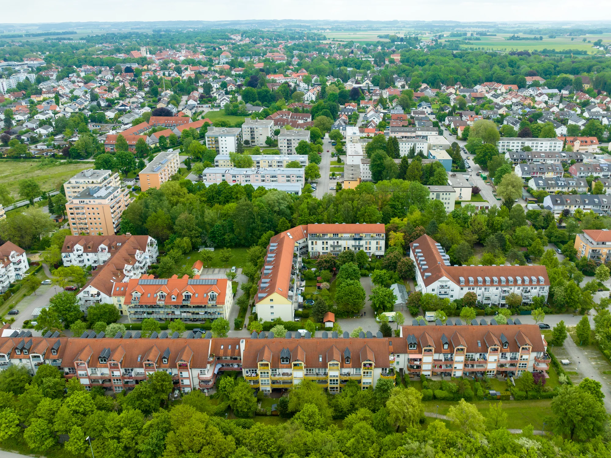 Luftaufnahme einer grünen Wohnsiedlung mit roten Dächern