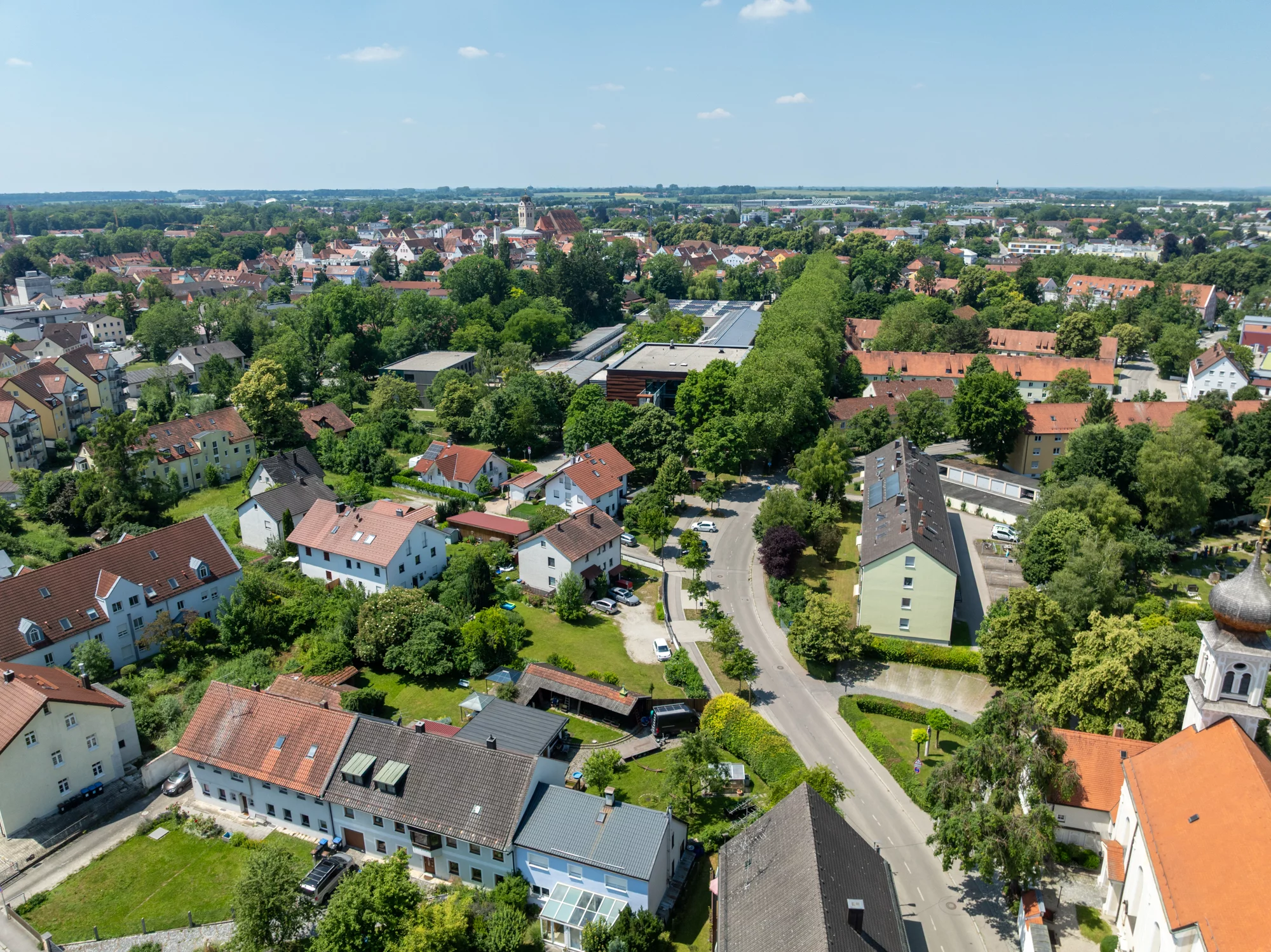 Luftaufnahme einer grünen Kleinstadt mit roten Dächern
