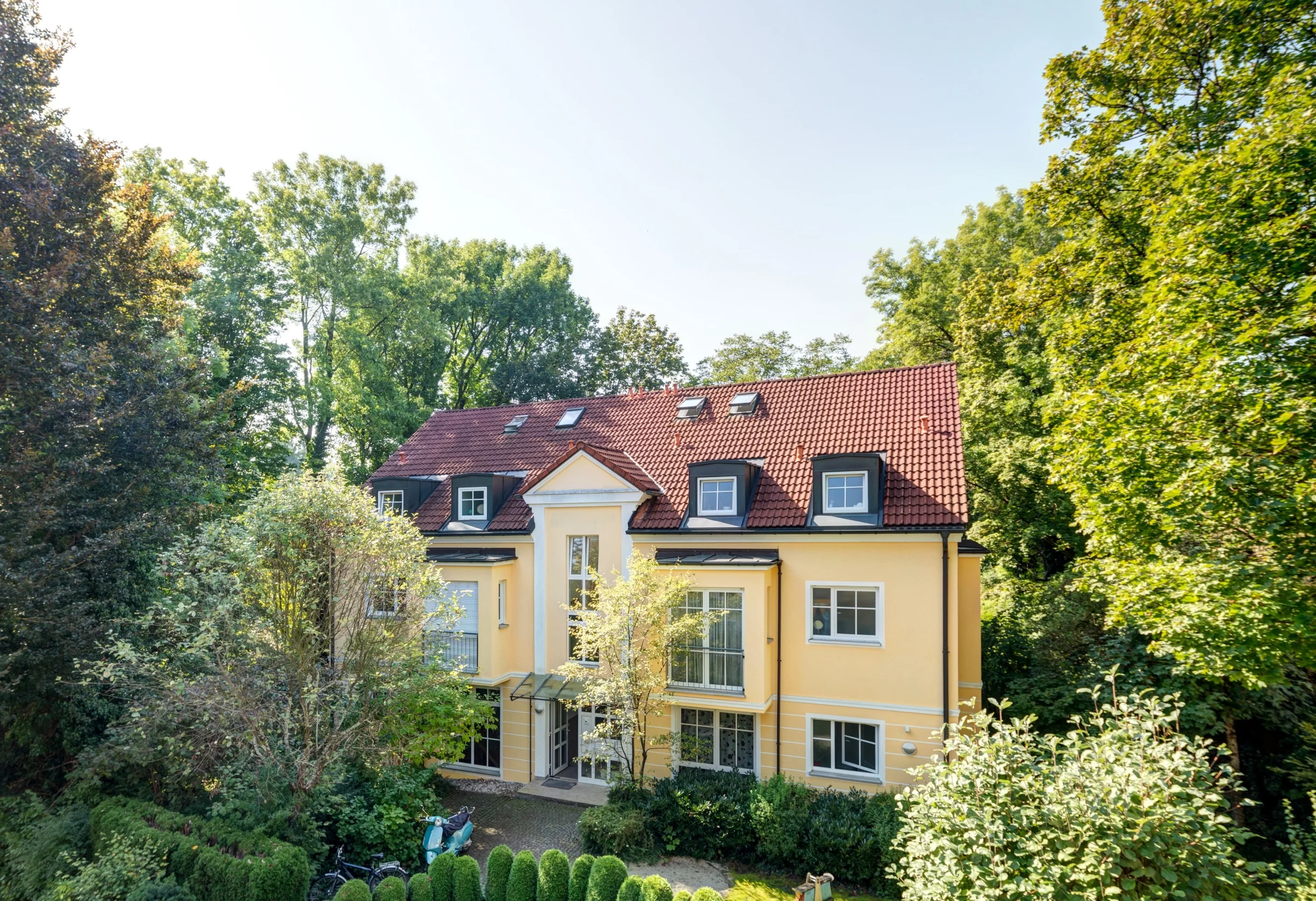 Gelbe Villa mit rotem Ziegeldach im Grünen