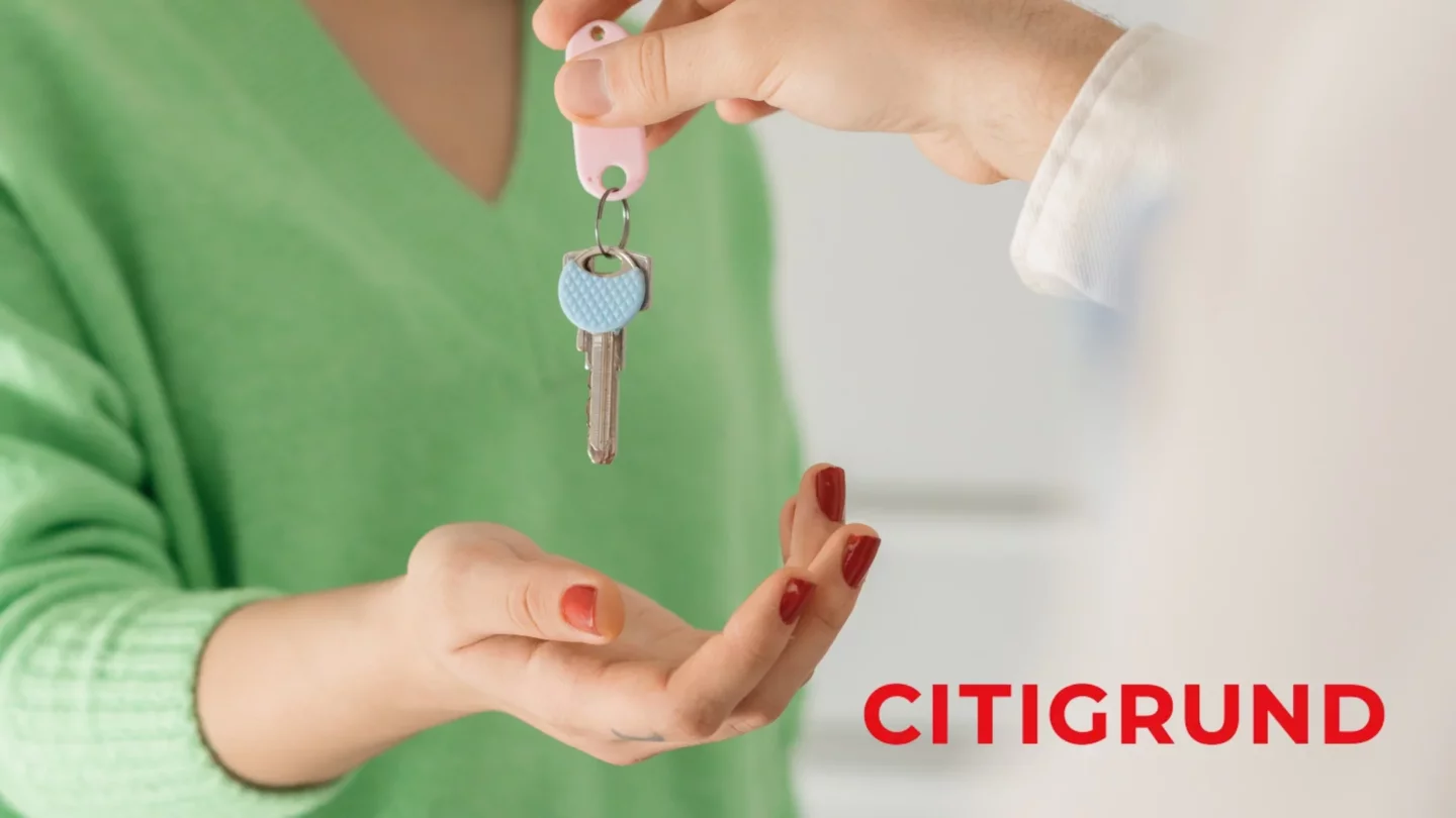Schlüsselübergabe vor grünem Hintergrund mit Citigrund-Logo
